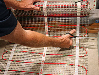 Cutting the mesh backing of floor heating mat.