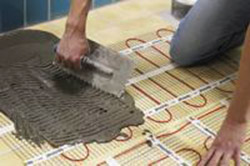 Applying thinset directly over radiant floor heating cable in mats.